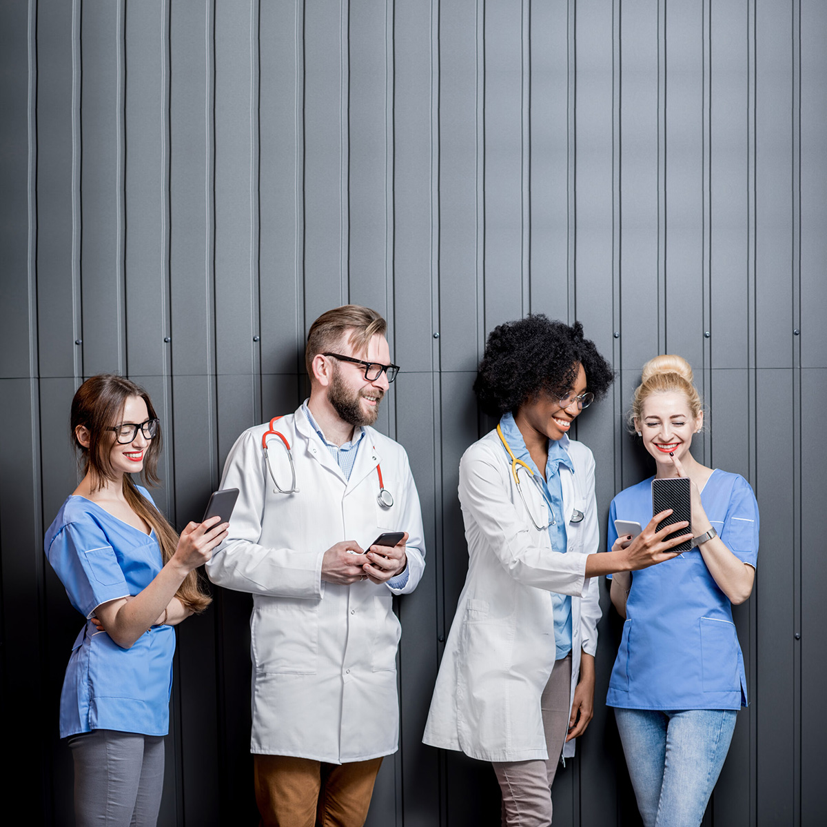 Group of young doctors looking at their mobile phones.