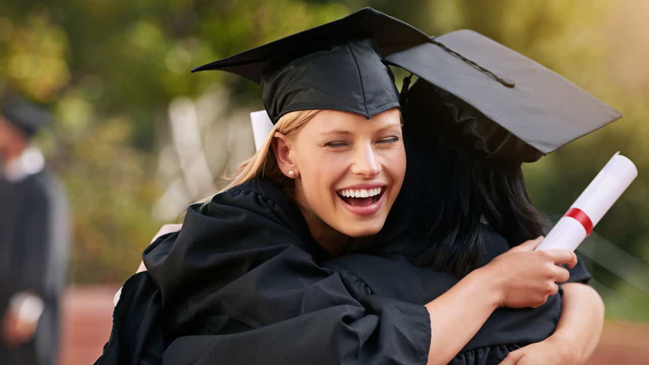 Blonde female hugging her friend after graduating 