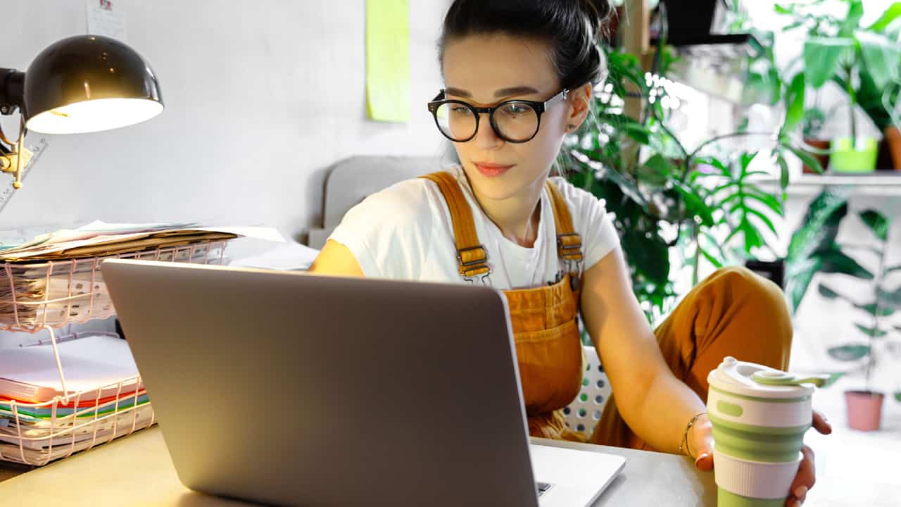 Young lady sitting in her home looking at laptop.