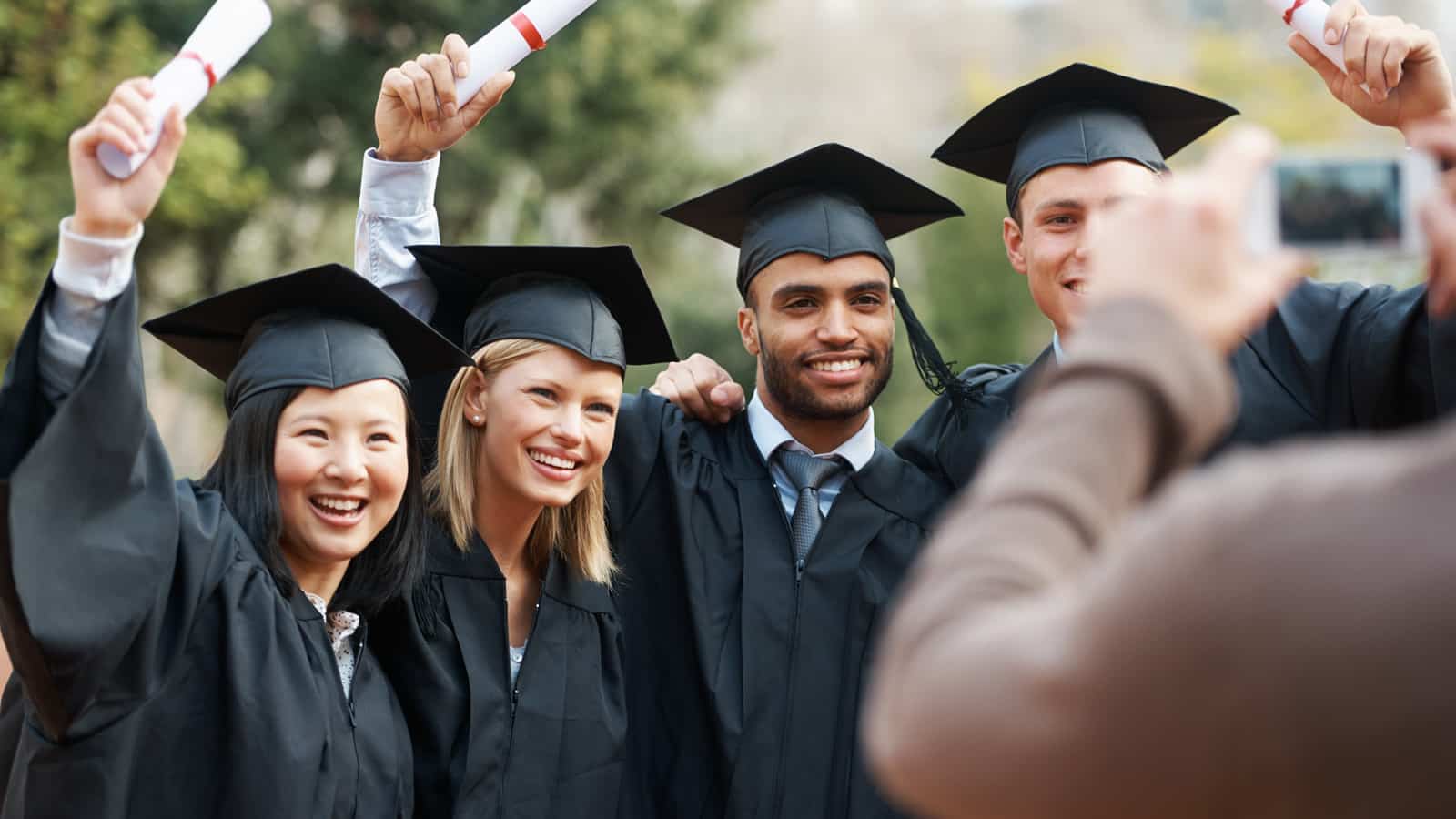 Group of young students with diplomas.