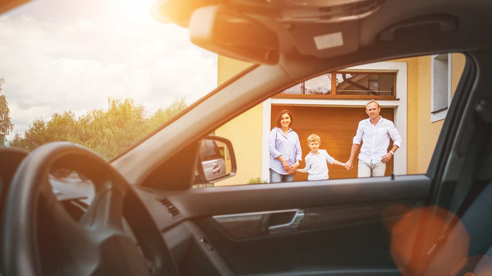 Couple standing in front of new home with car in the foreground.